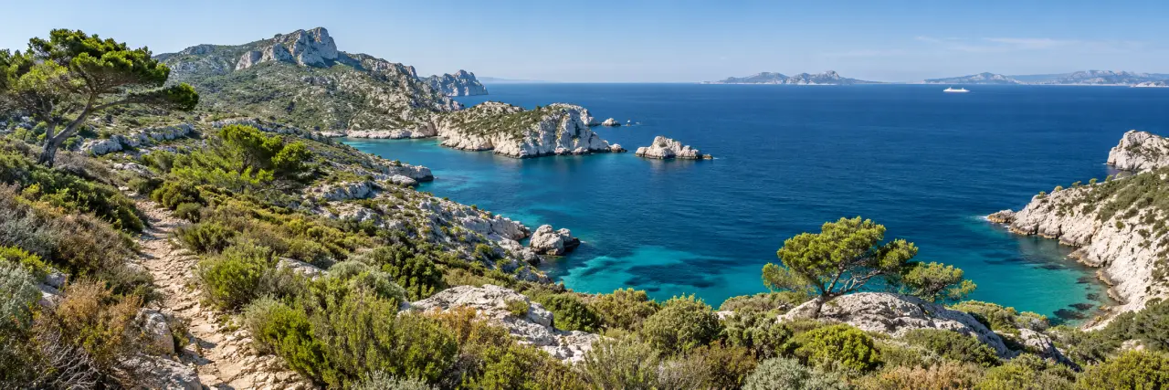 Paysage d’une île de Méditerranée avec maquis, sentier côtier et ferry